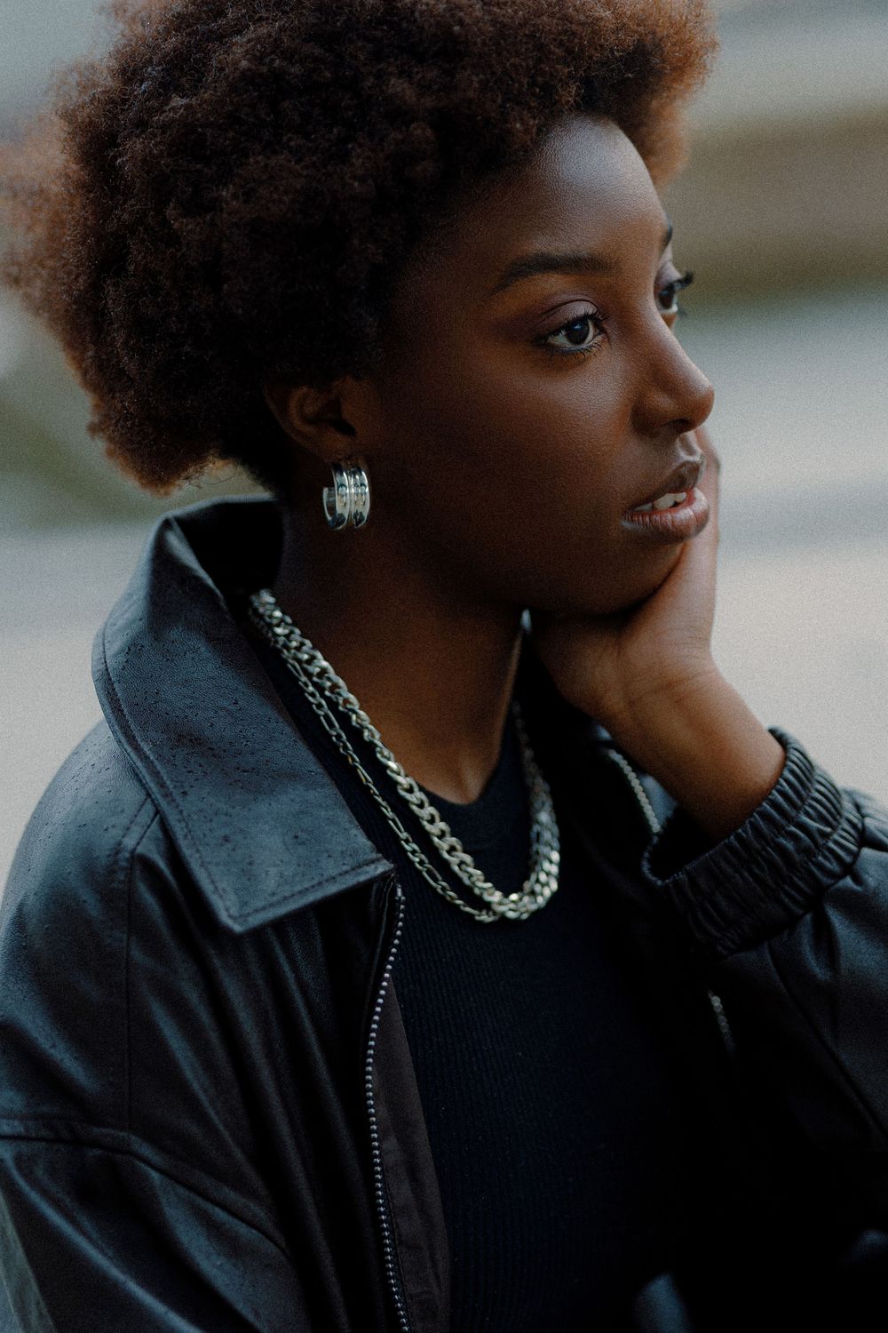 Profile shots showing a person with natural hair wearing a black leather jacket and silver jewelry.