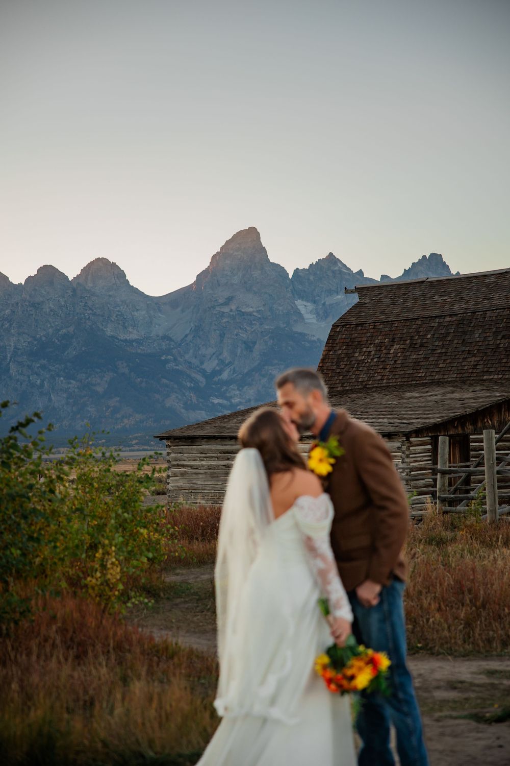 Elopement couples shares kiss in front of the grand Teton in Grand Teton National Park