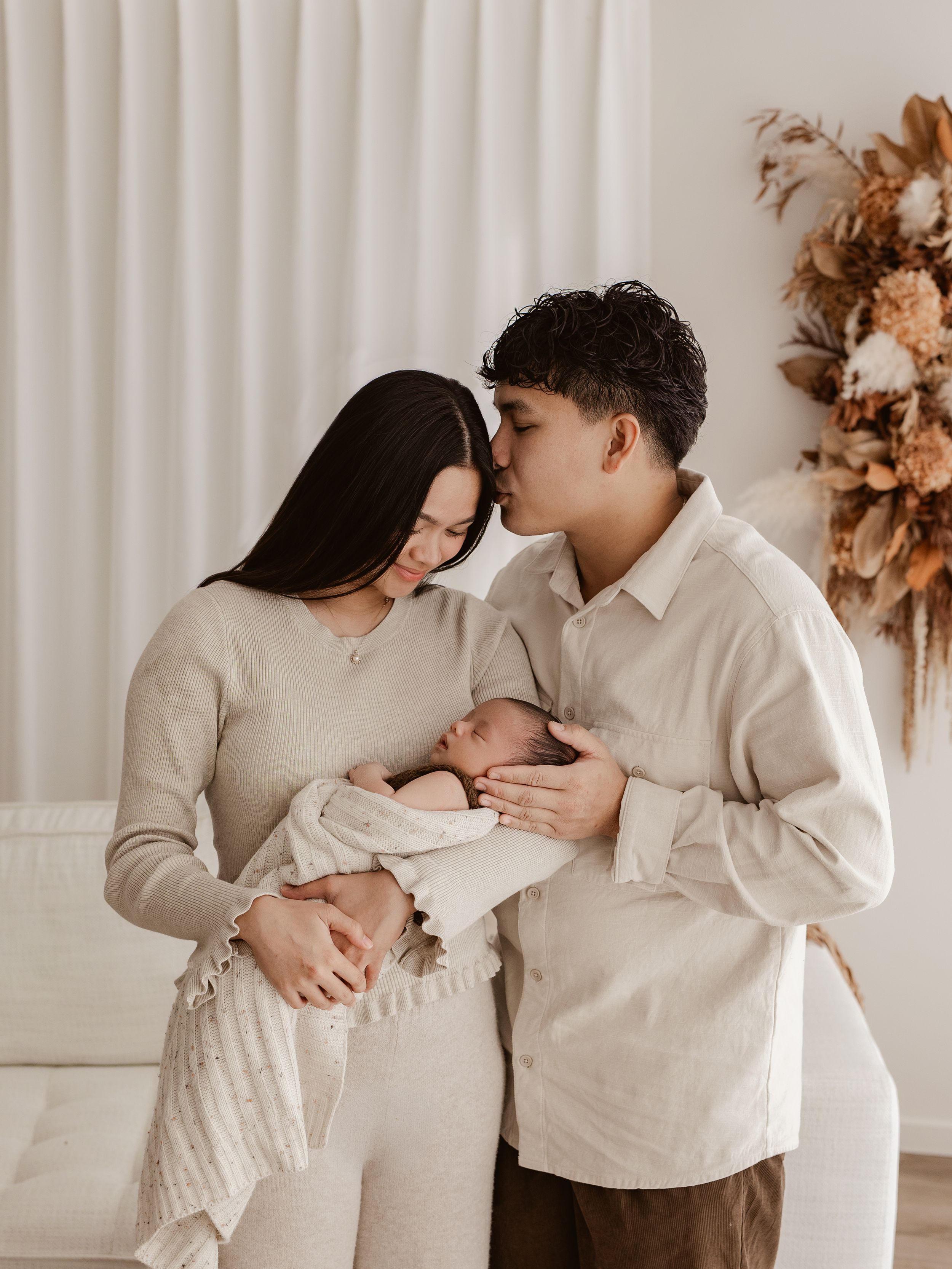 Intimate family moment with parents cradling young child in white room.