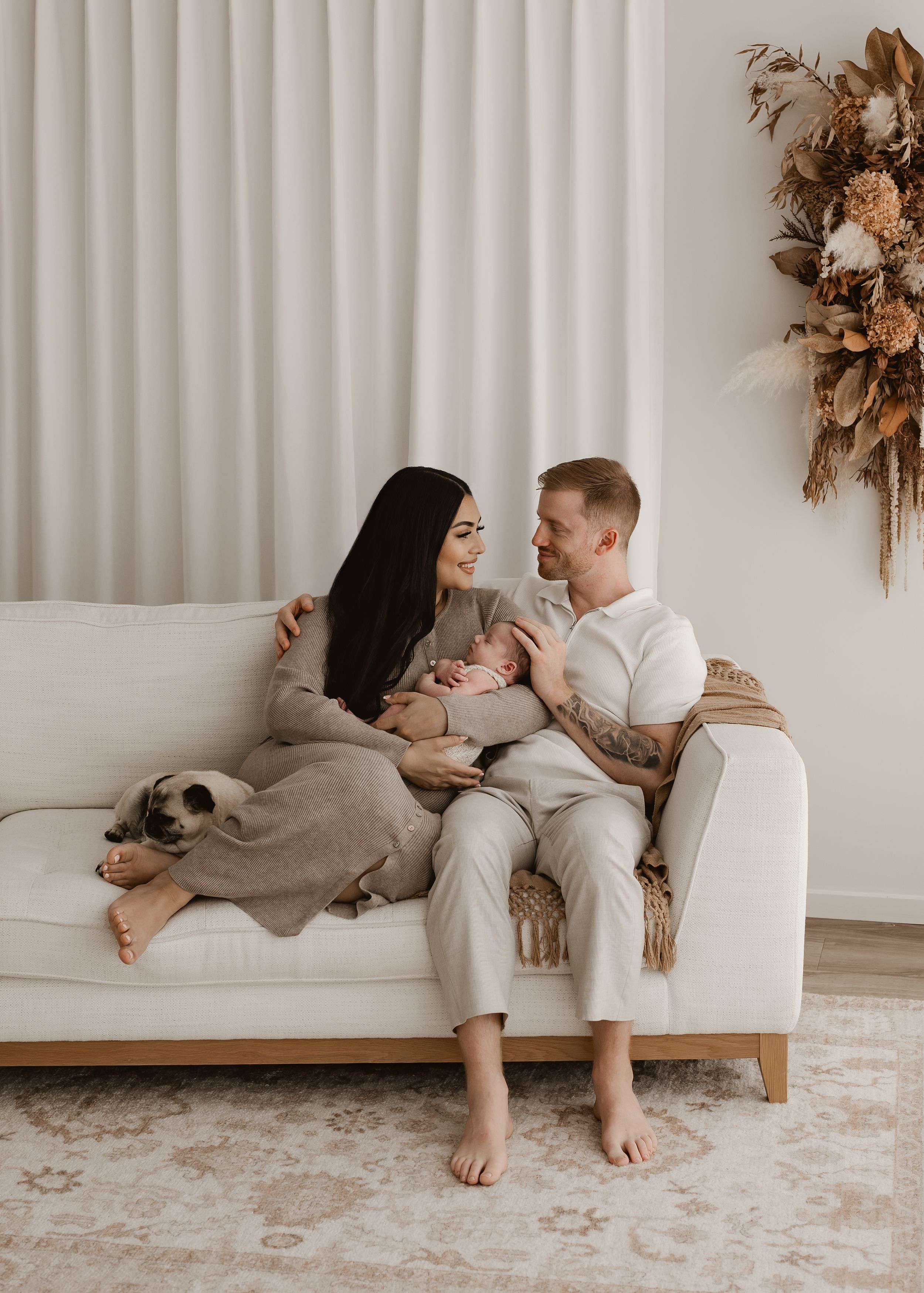Intimate family moment with parents cradling young child in white room.