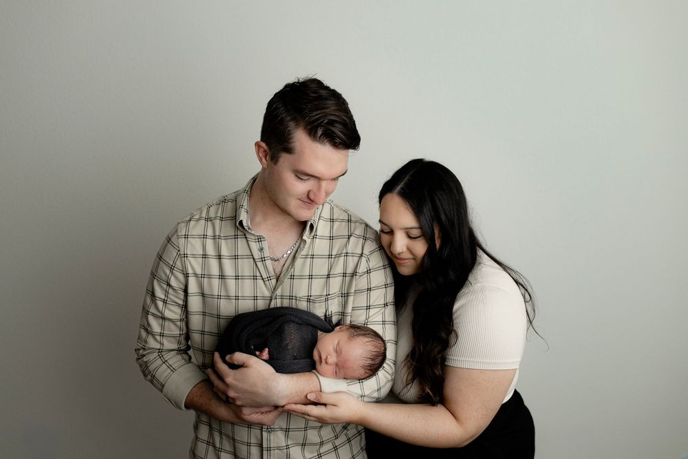 A minimalist studio photography session showing intimate family moments against a neutral background.