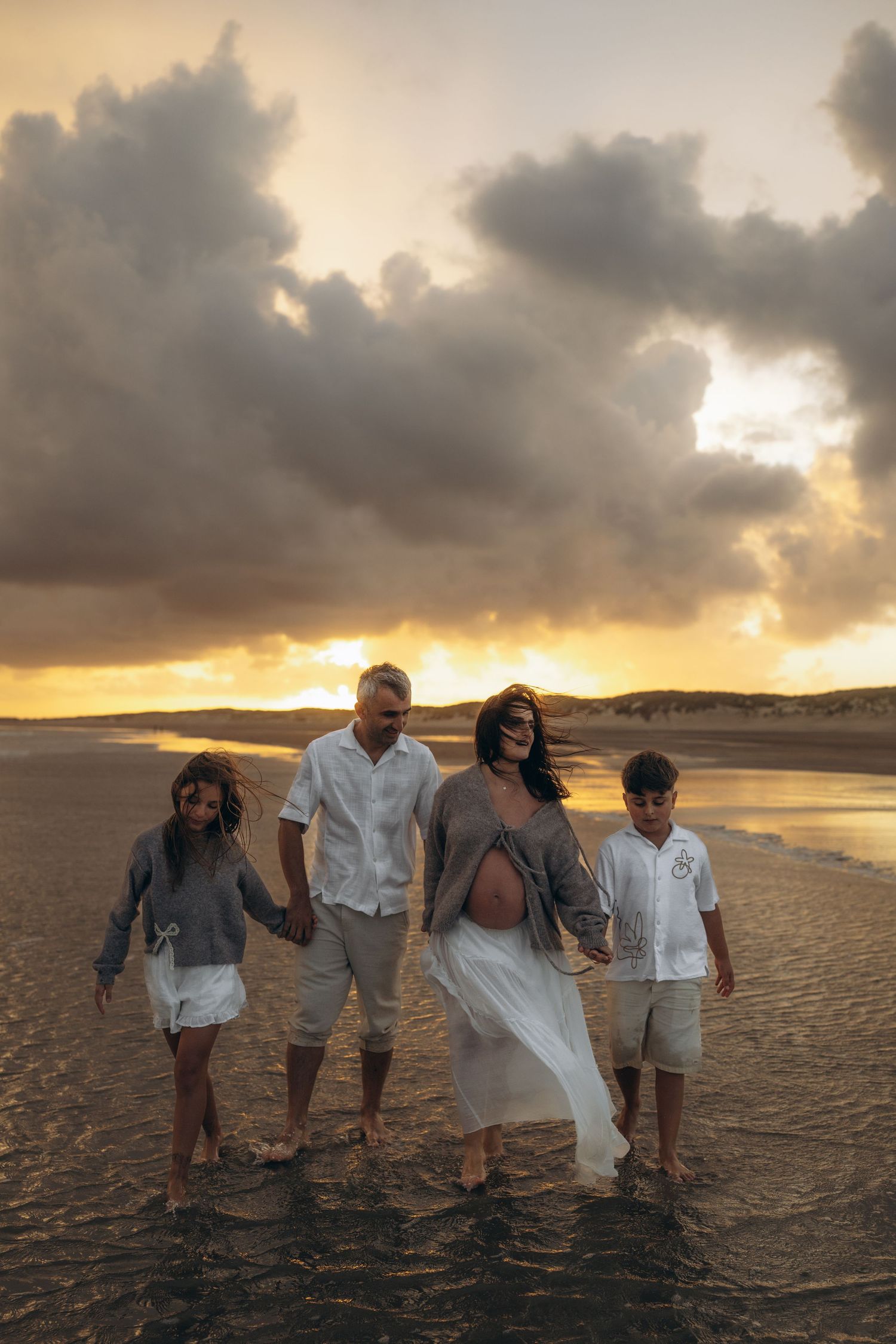 A family walking on the beach during a maternity photo session with Forever Ours Photography in Camber Sands, UK