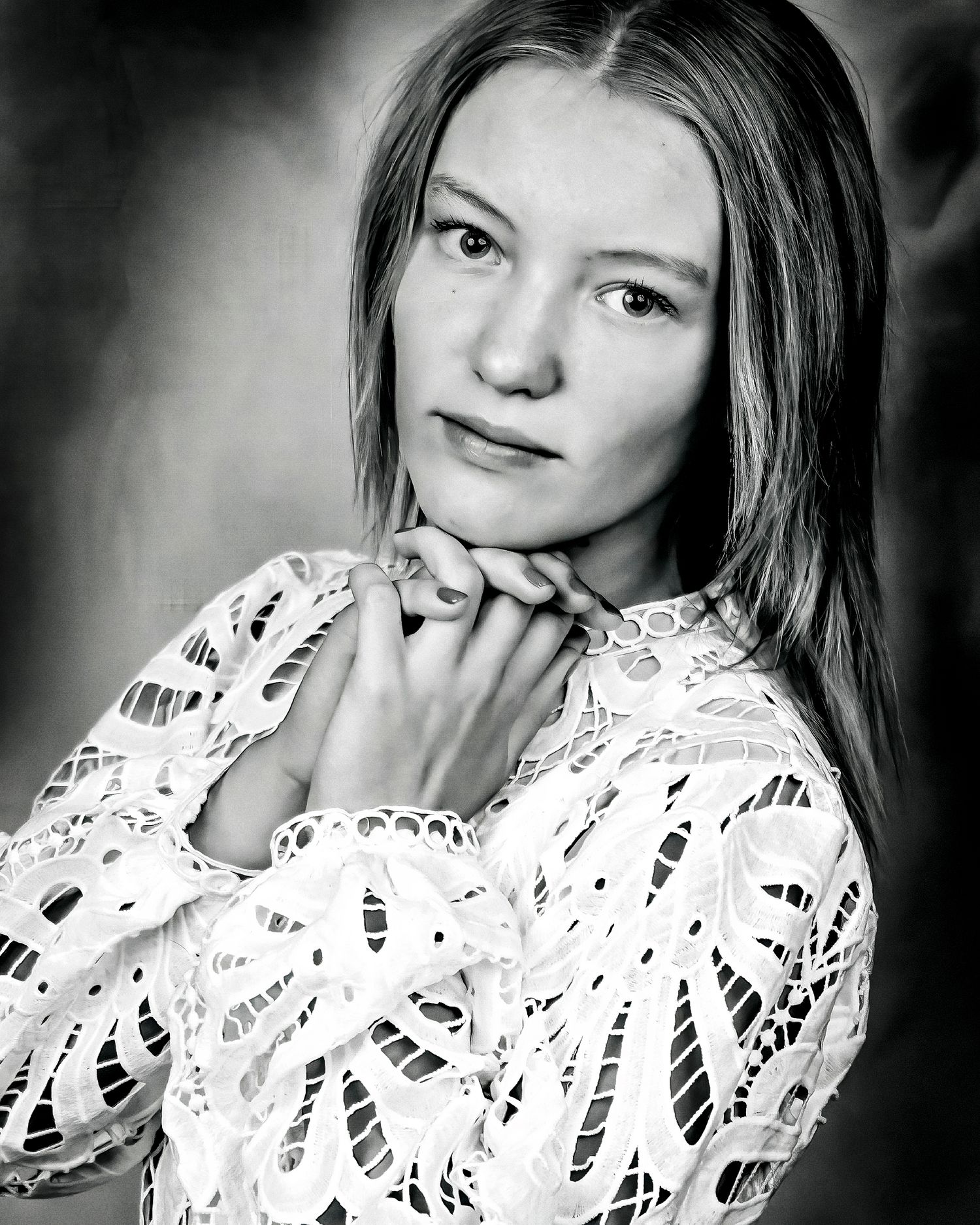 Black and white portrait in white lace dress with gentle expression.
