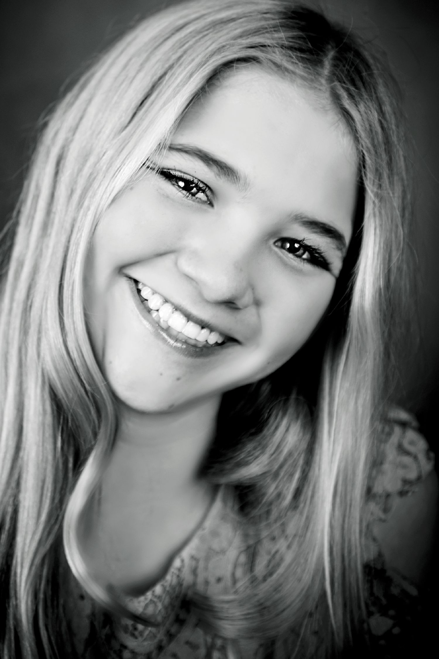 Black and white close-up portrait with bright smile and long hair.