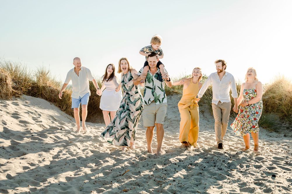 On a sunset beach on Hayling Island, Hampshire, a family walk hand in hand walking through the sand laughing during their photoshoot.