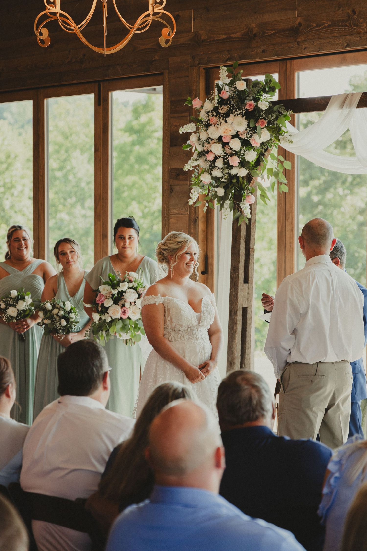An intimate indoor wedding ceremony with floral decorations and bridesmaids in soft blue dresses.