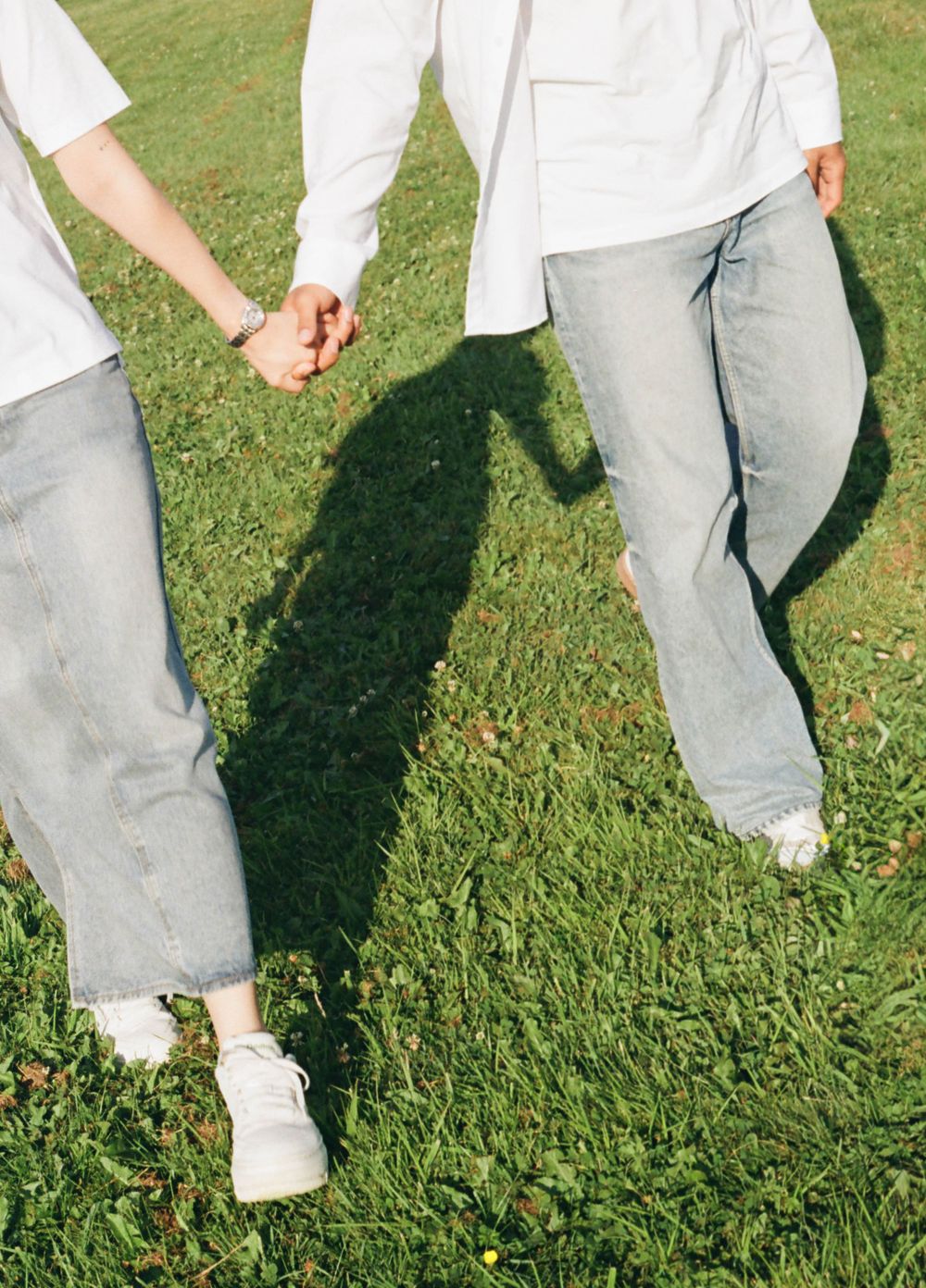Close-up of legs and feet walking through green grass on a sunny day.