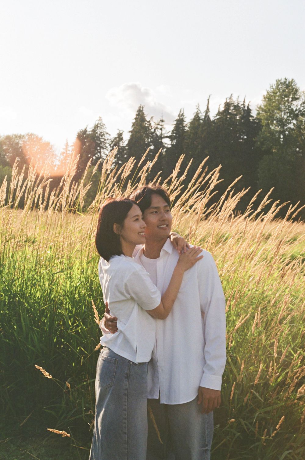 Two people embrace among golden wheat fields during sunset.