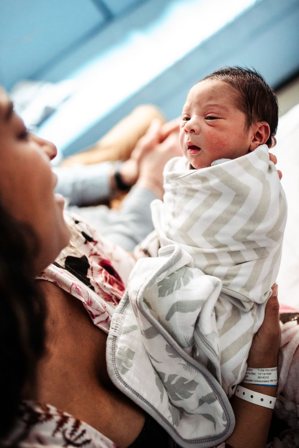 Newborn baby wrapped in chevron pattern blanket during hospital photo session.