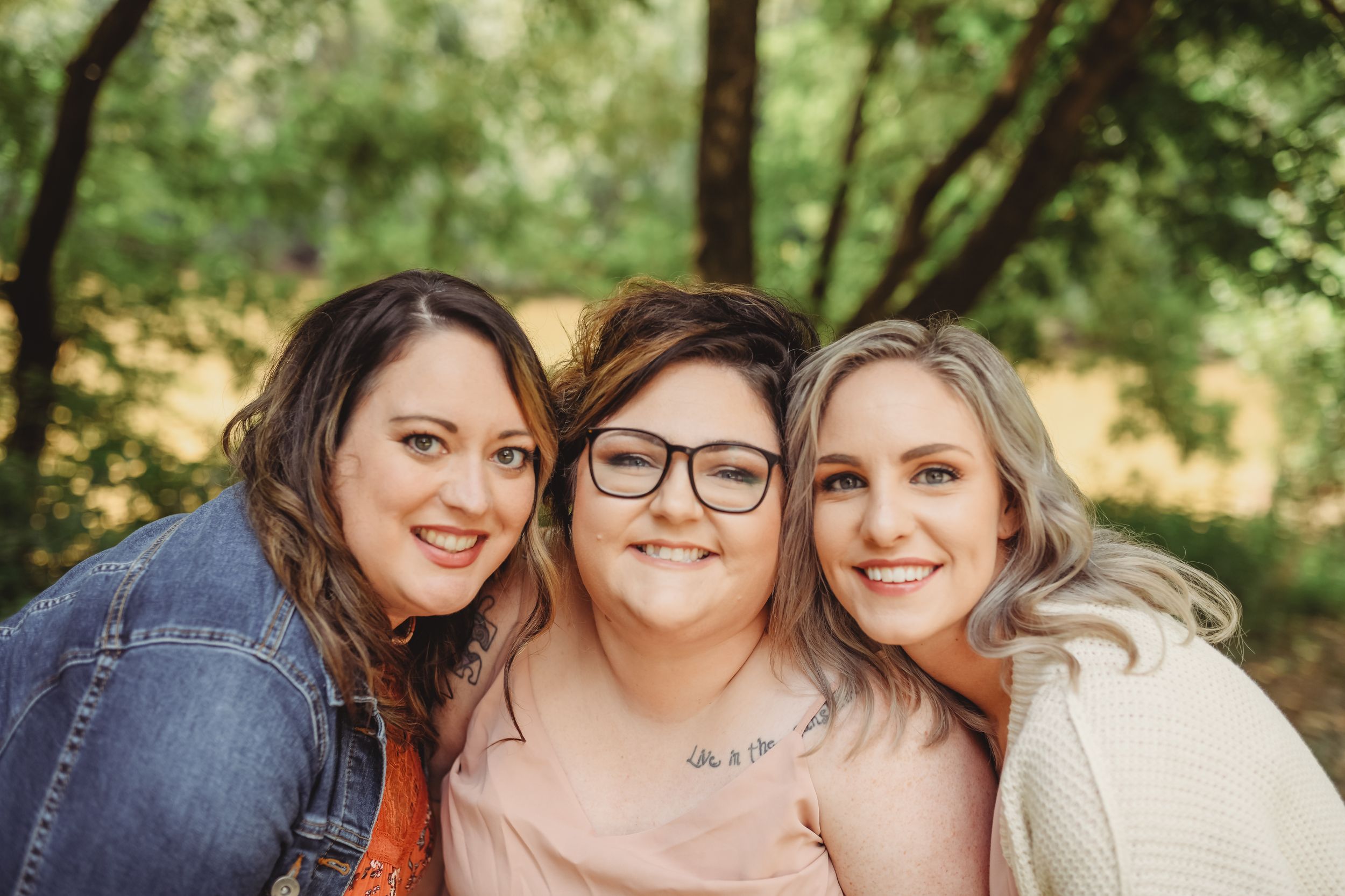 Three friends share a close moment together outdoors during a photo session.