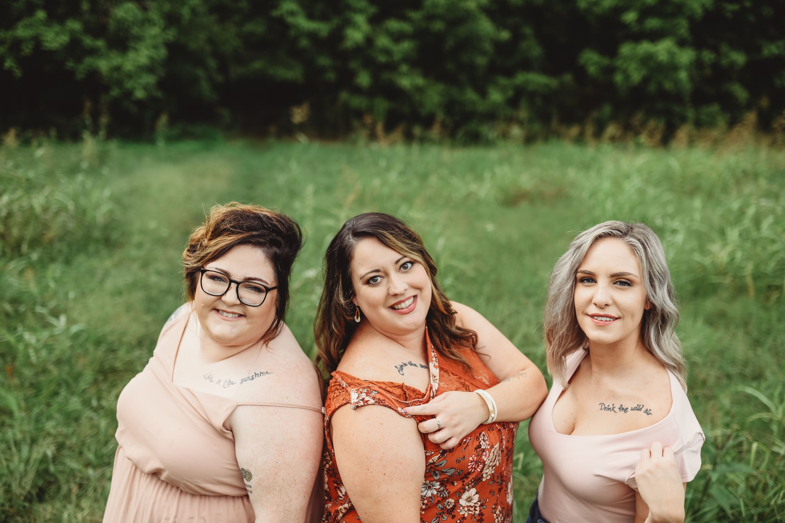 Three friends pose together outdoors wearing coordinated casual outfits.