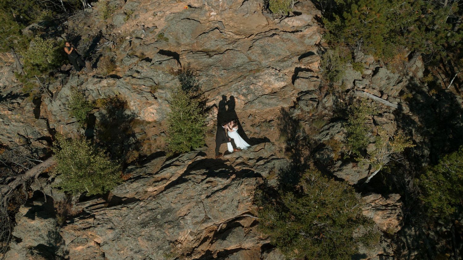 A rocky mountain landscape with steep cliffs and green vegetation growing along rugged terrain.