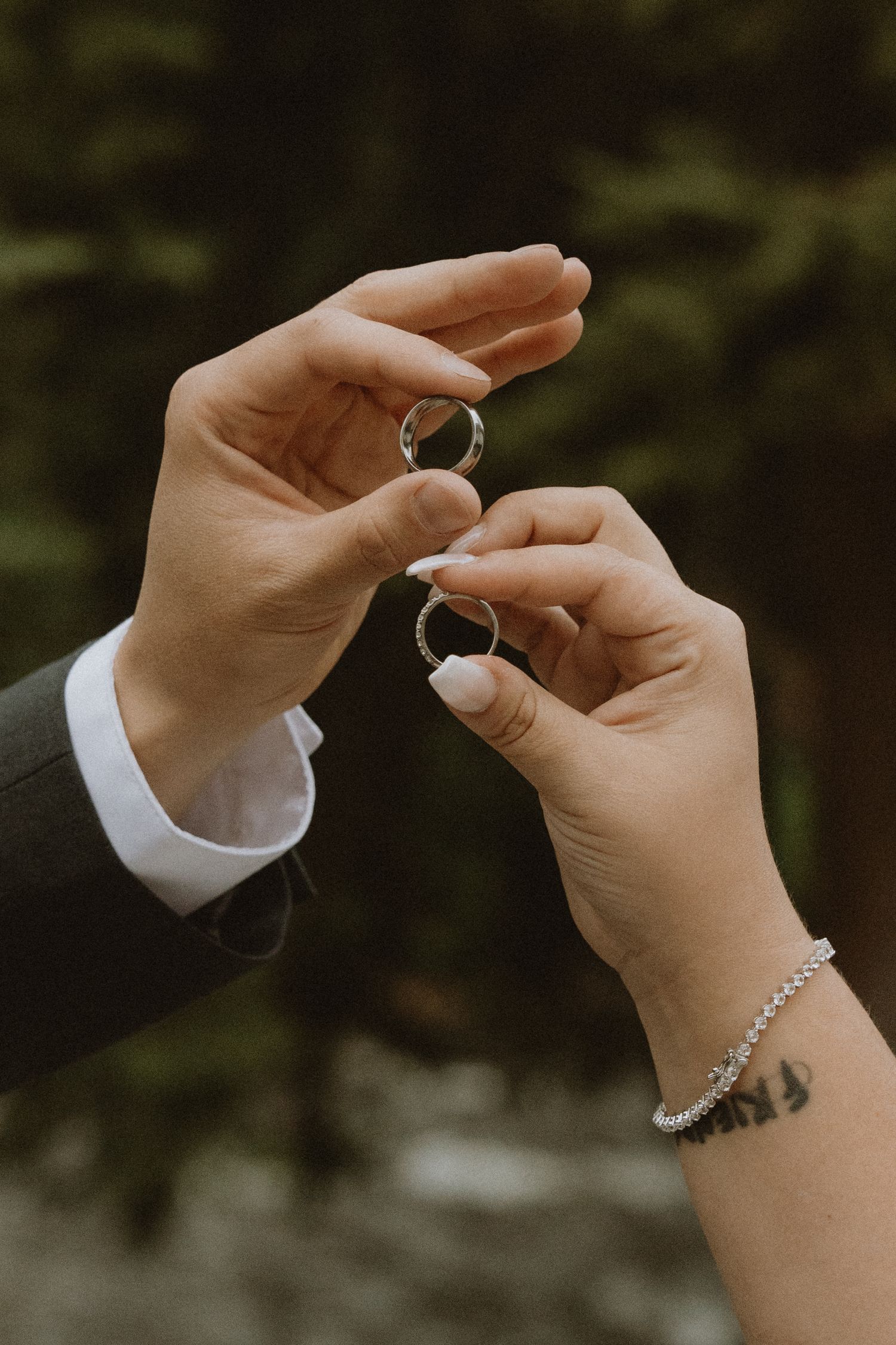 Close up of hands exchanging wedding rings in a romantic outdoor ceremony.