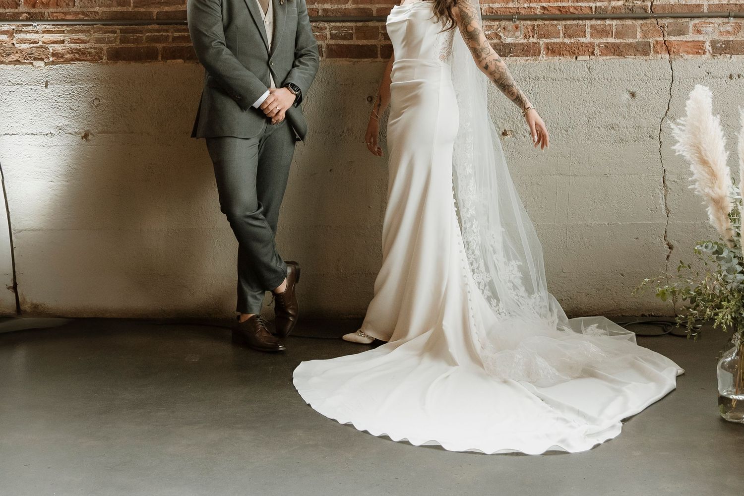 Wedding couple silhouetted against brick wall and windows in industrial venue space.