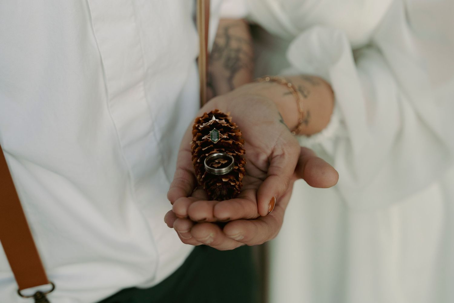 A person in white clothing holds soil and small plants in their hands, demonstrating gardening or planting activities.