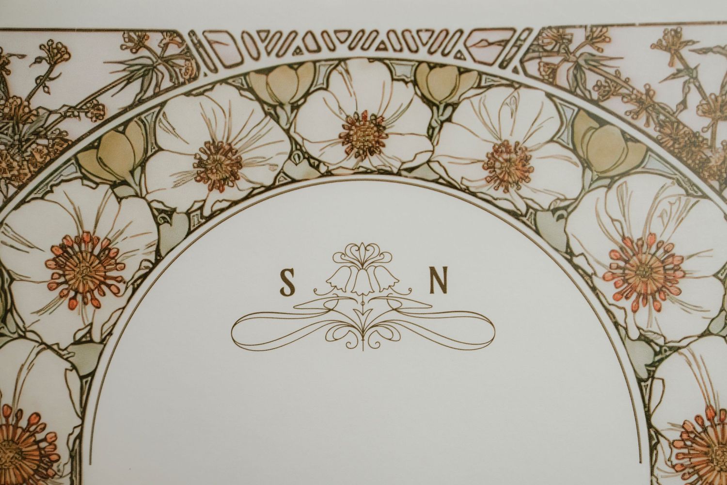Ornate Art Nouveau style floral border design with delicate curves and sunburst patterns in gold and beige tones.