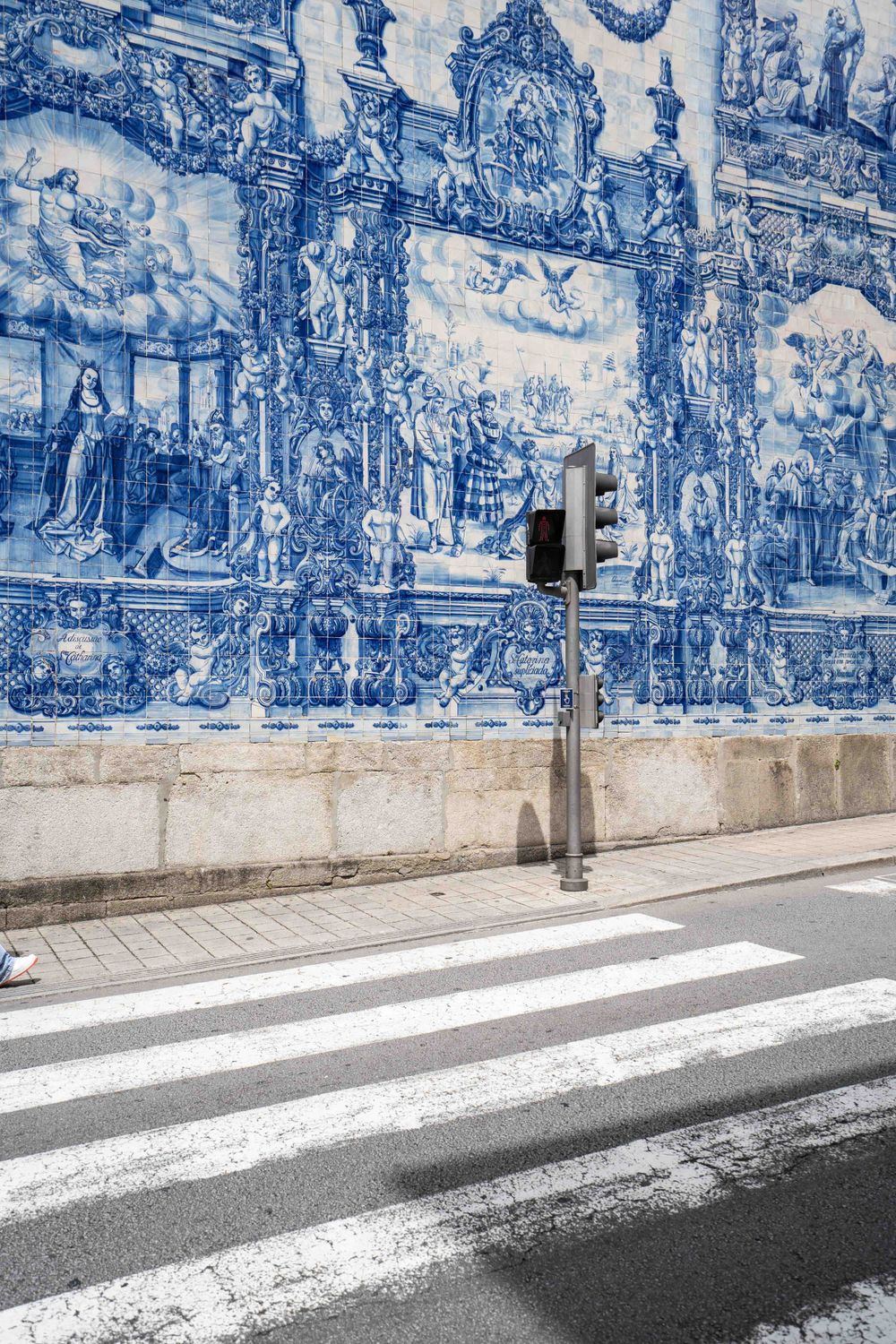 Stunning blue azulejo tile murals decorating church wall with crosswalk in foreground.