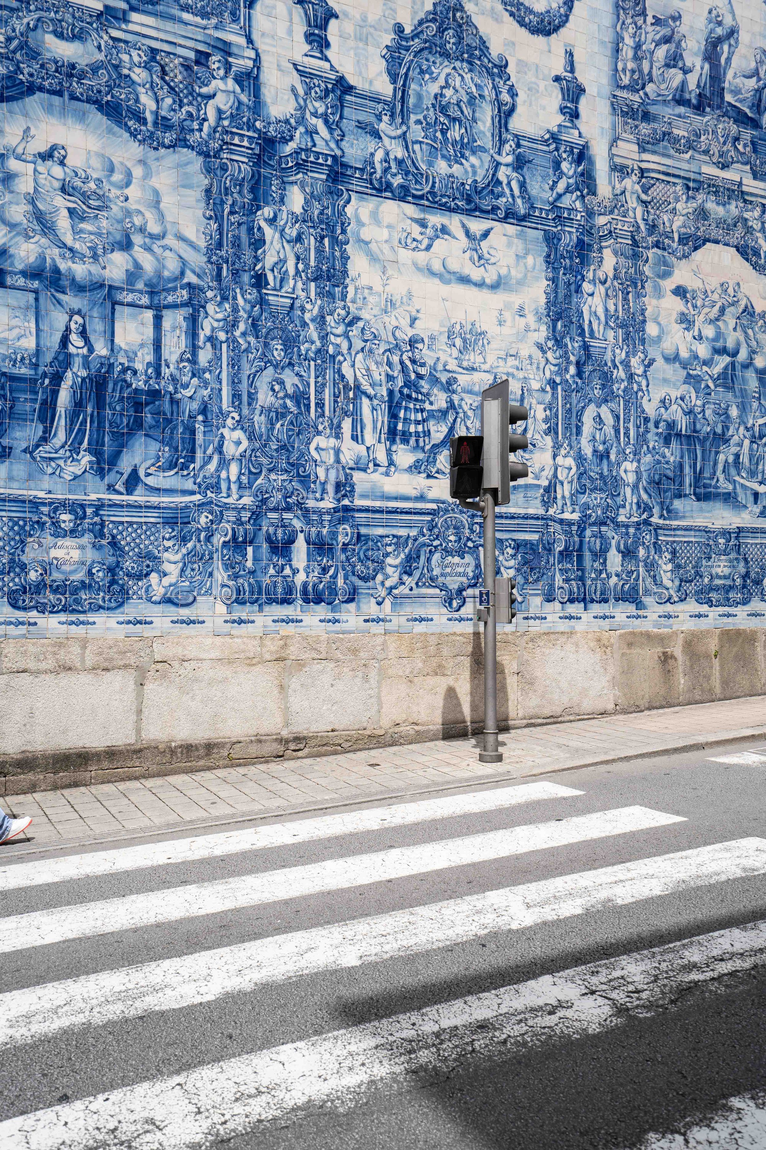 Stunning blue azulejo tile murals decorating church wall with crosswalk in foreground.