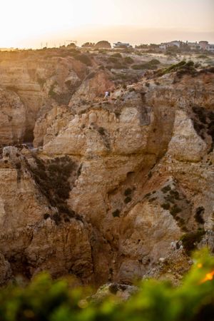Sunset view of rugged limestone cliffs with buildings perched along the coastal edge.