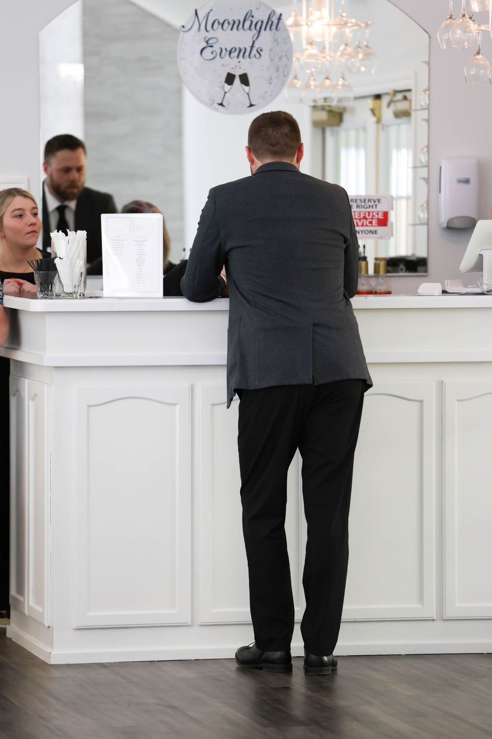 Man in gray suit standing at white reception desk at Moonlight Events wedding venue.