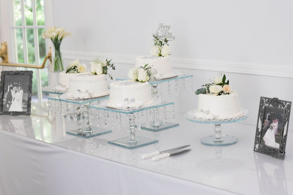 Elegant wedding dessert table with multiple white cakes on crystal stands with floral decorations.