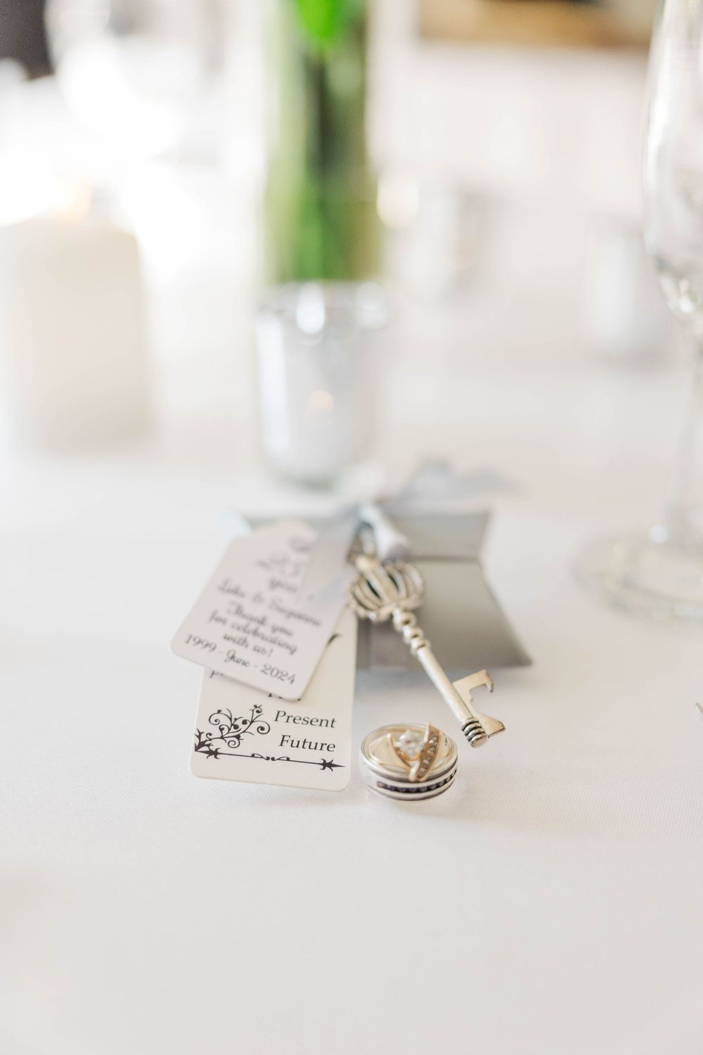 Wedding favor key charm with Present and Future tag on white table at reception.