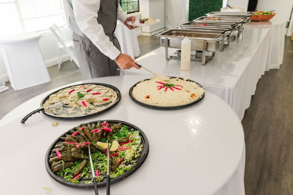 Catering staff presenting colorful appetizer platters at elegant wedding reception buffet table.