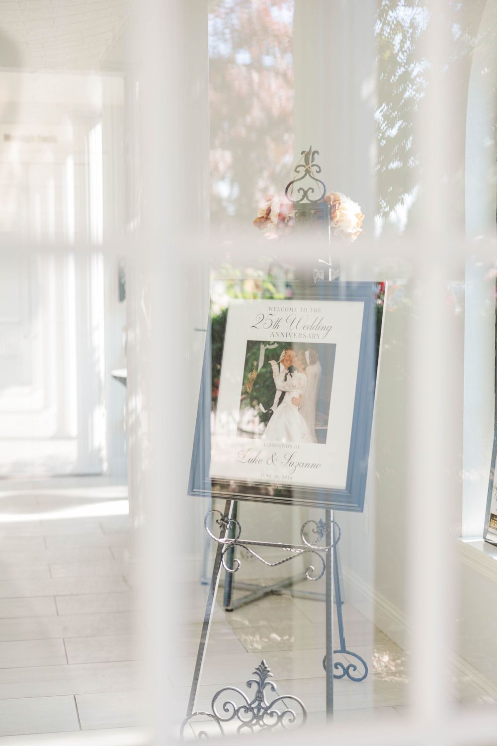 Silver easel displaying a 25th wedding anniversary framed photo in a bright white venue.