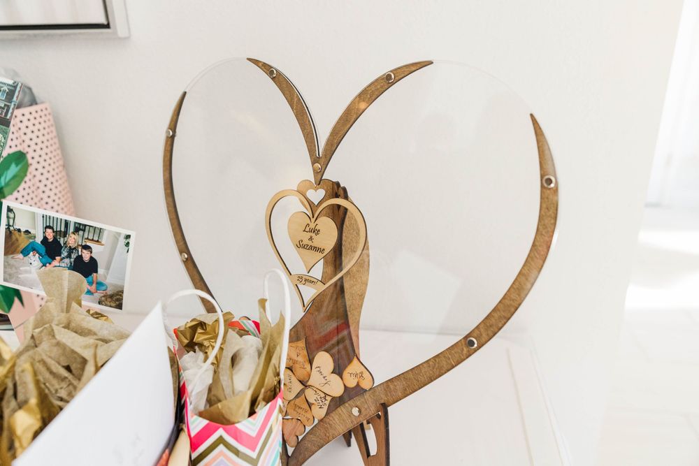 Wooden heart-shaped wedding guest book display with laser-cut decorative design and small hearts.