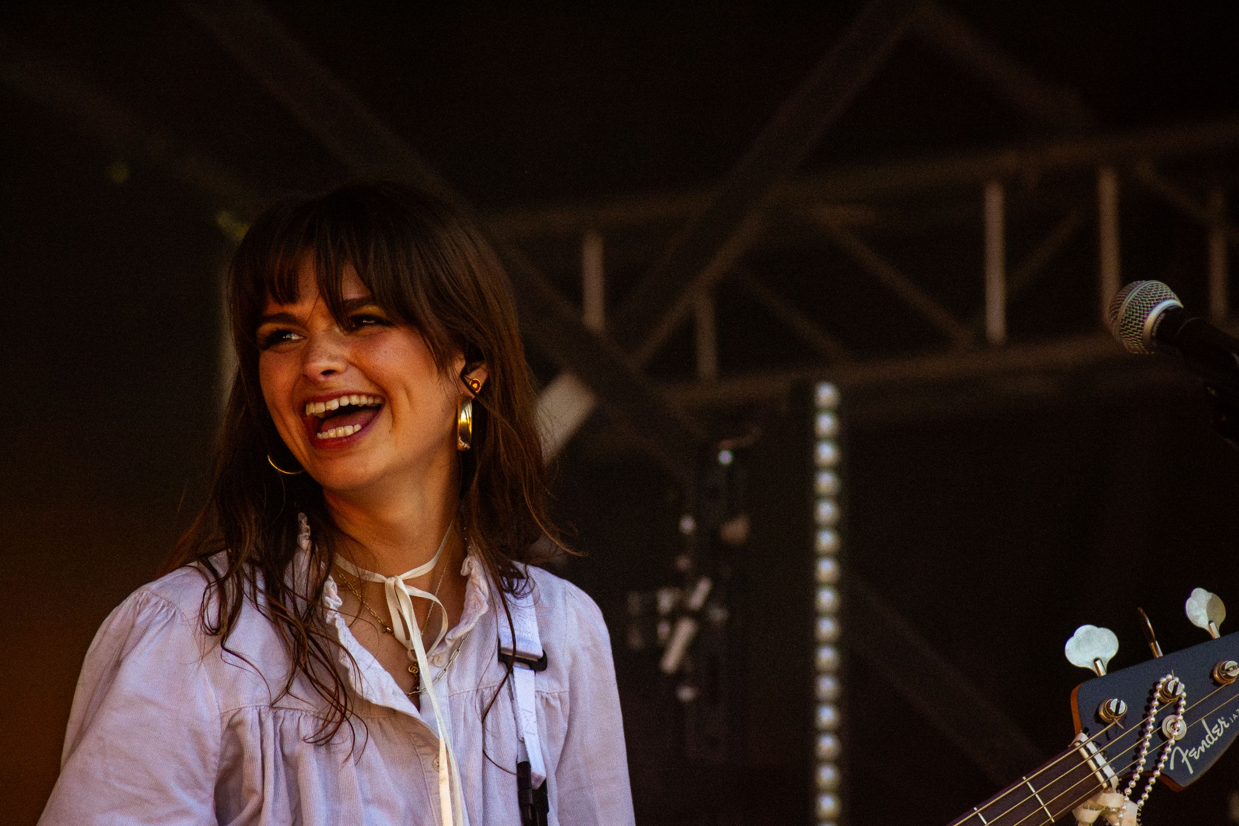 Candid performance shot of musician laughing during stage show with dark lighting.