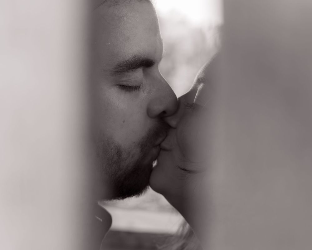 A soft, dreamy black and white close-up of a couple sharing an intimate kiss.