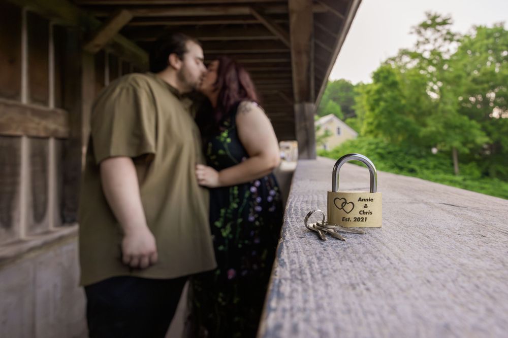 A couple shares a romantic kiss on a covered porch with a picnic basket nearby.