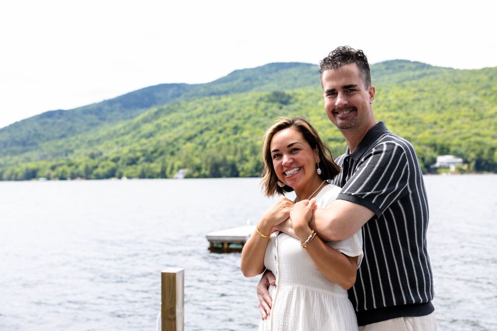 Couple sharing intimate moments by a lake with mountains in the background.