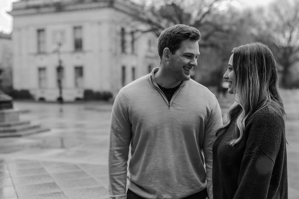 Couple walking together in casual attire on a black and white photo.