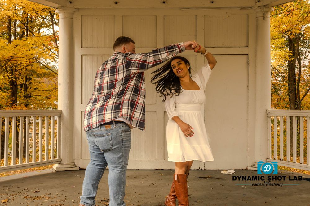 Couple dances on white porch during fall engagement photoshoot.