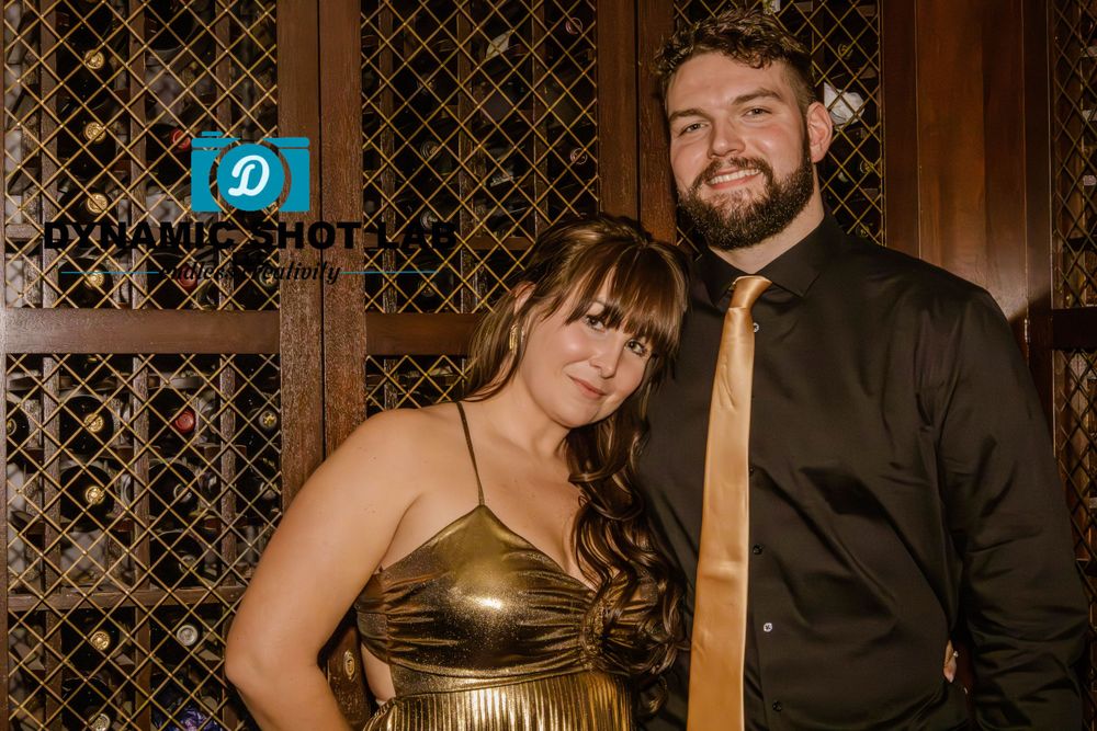 A couple poses for a formal portrait in front of a decorative lattice wall.
