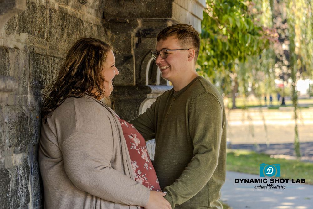 Autumn engagement photo session under stone archway with golden foliage.