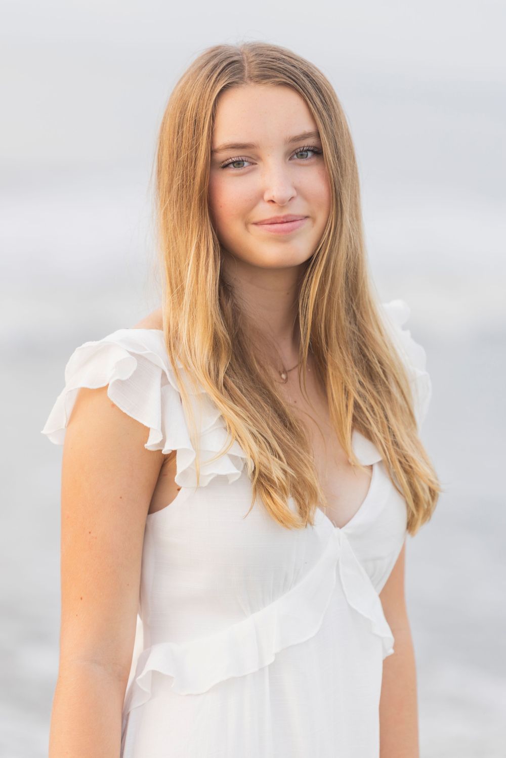 Headshot of a woman in a white ruffled blouse with blonde hair against a light background.