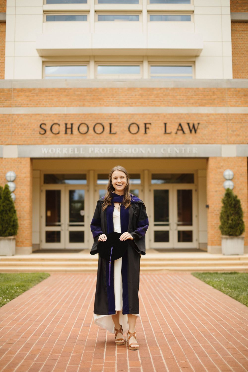 Graduate portraits taken in front of School of Law building entrance on brick walkway.