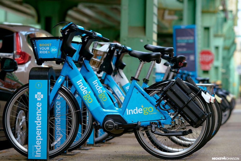 Row of blue rental bikes parked in a bike share station.