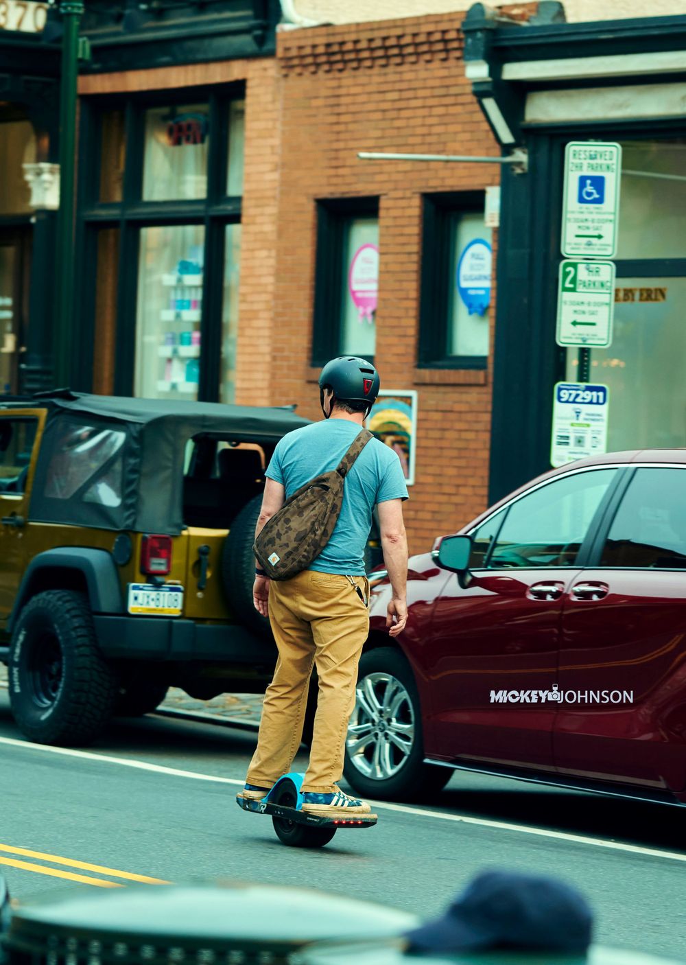 Person skateboarding past parked cars on an urban street.