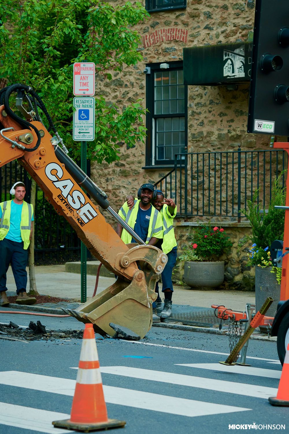 Construction worker installing crosswalk markings on a street near a stone building.
