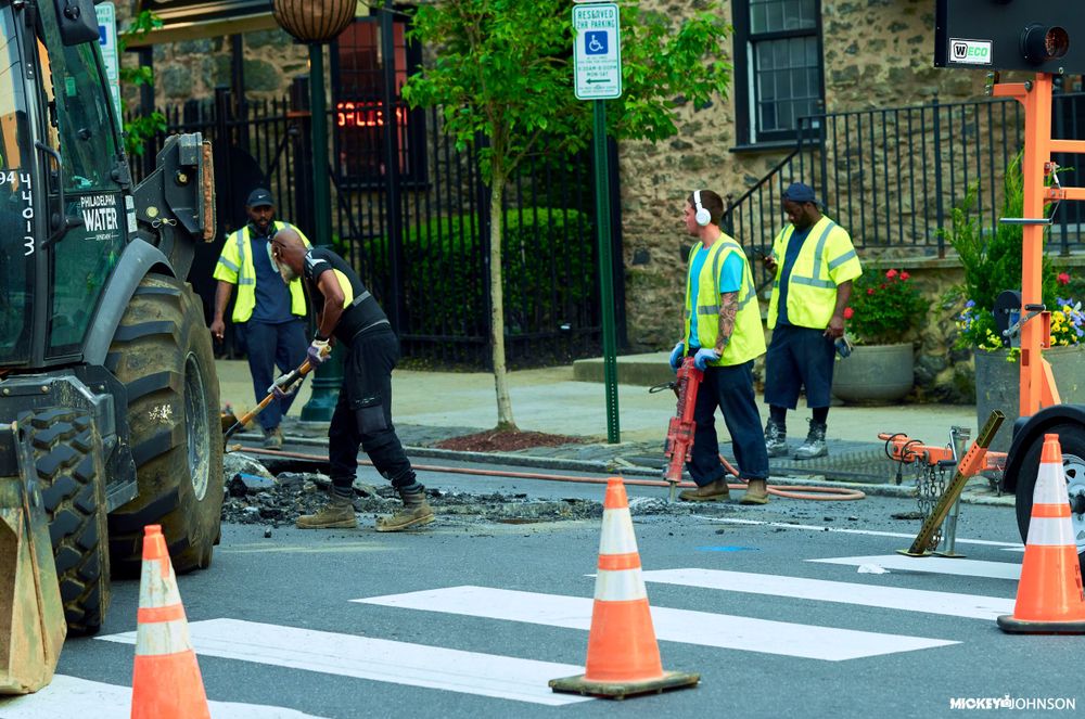 Series of orange traffic cones lined up on a freshly painted crosswalk.