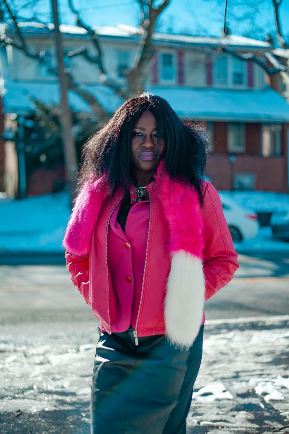 Winter street scene with bright pink jacket against snowy background.