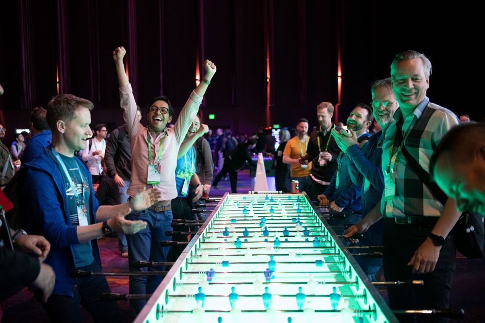 Energetic foosball match with players celebrating under colorful lighting.