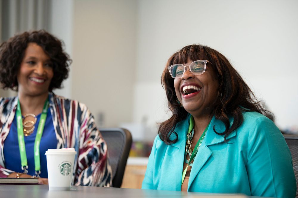 Two professionals share a lighthearted moment during a coffee break at a business meeting.
