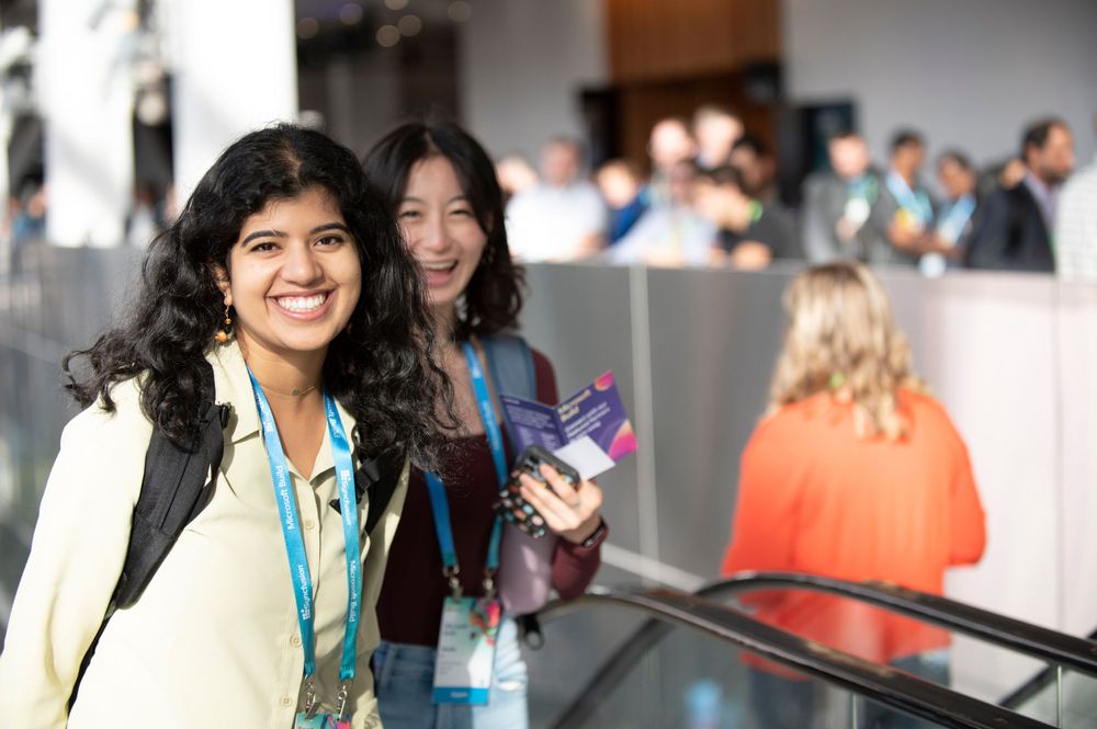 Conference attendees with badges networking in bright indoor venue.