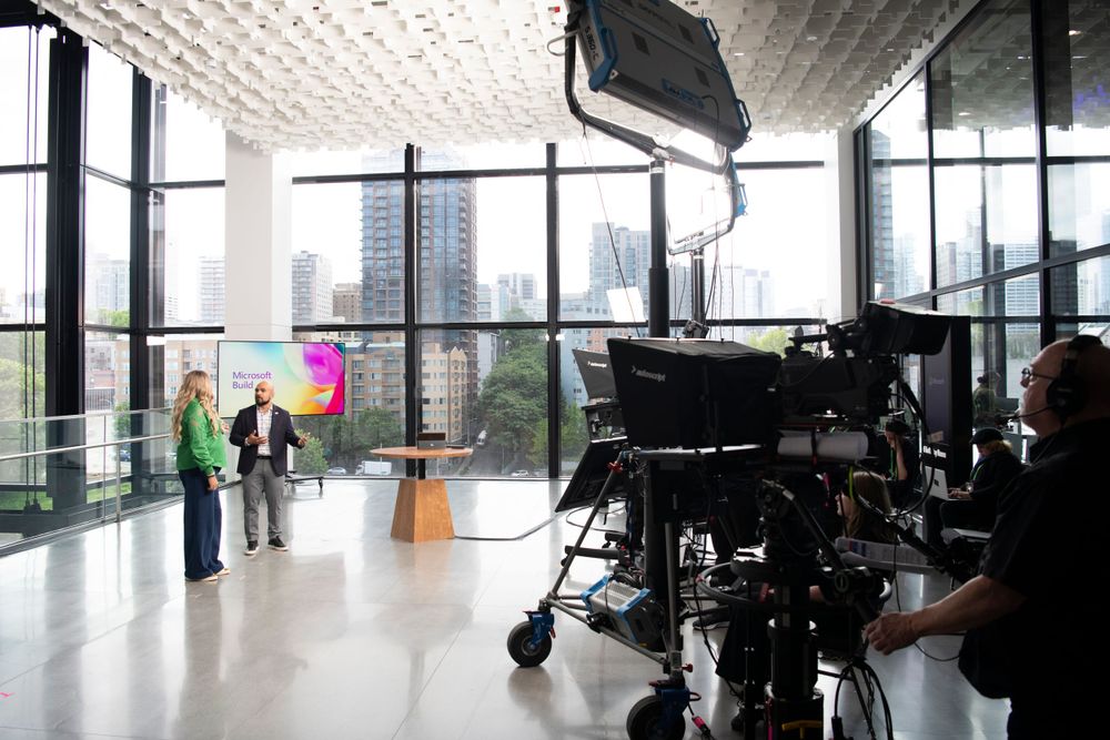 Behind-the-scenes view of a professional video production setup in a modern office space with city views.