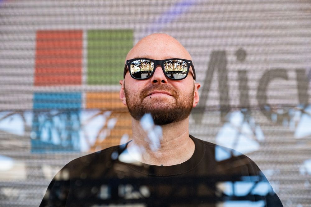 Close-up portrait with reflective glasses against industrial background.