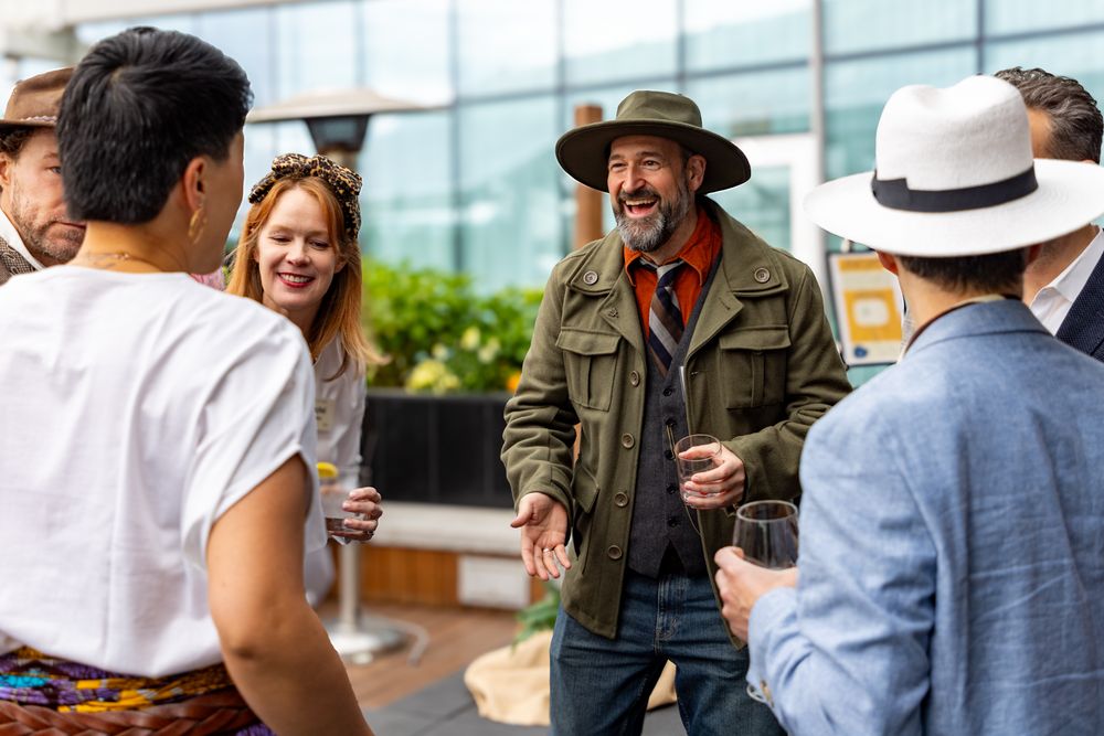 Diverse group of people engaged in outdoor community conversation and networking.